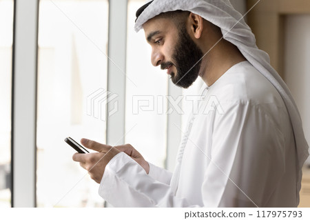 Positive young Arab businessman using wireless Internet communication Positive young Arab businessman using wireless Internet communication 117975793
