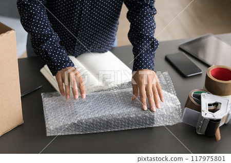 Small business owner packing package for dispatch to client 117975801