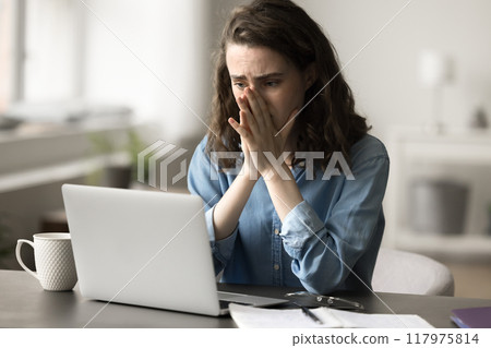 Woman looking at laptop screen read terrible news feels stressed 117975814