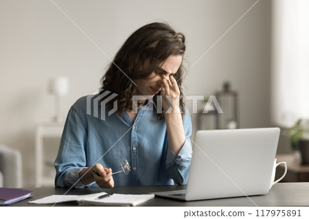Tired woman feels eye strain after long usage of laptop Tired woman feels eye strain after long usage of laptop 117975891