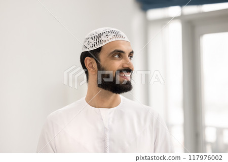 Positive pensive handsome Arabian man posing in home apartment Positive pensive handsome Arabian man posing in home apartment 117976002