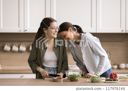 Happy mother and adolescent daughter preparing vegetable salad 117976148