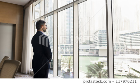 Serious confident business owner man in suit standing at window 117976211