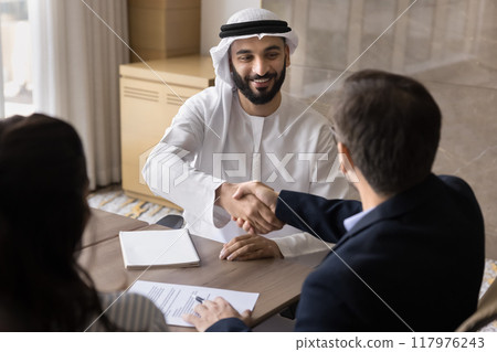 Happy confident Arabian company owner shaking hands with European colleagues 117976243