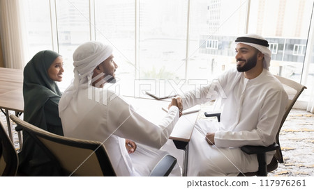Happy Arabian new company co-owners, partners shaking hands on meeting Happy Arabian new company co-owners, partners shaking hands on meeting 117976261
