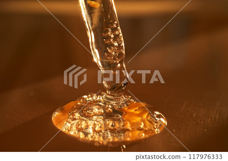 Pipette with serum shimmering in the sun on a beige background. 117976333