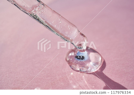Pipette with serum shimmering in the sun on a pink background. Pipette with serum shimmering in the sun on a pink background. 117976334