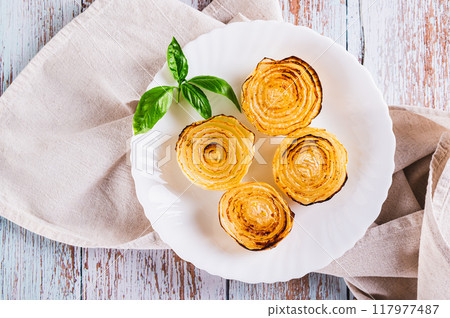 Close up of caramelized roasted onions and basil on a plate on the table top view Close up of caramelized roasted onions and basil on a plate on the table top view 117977487