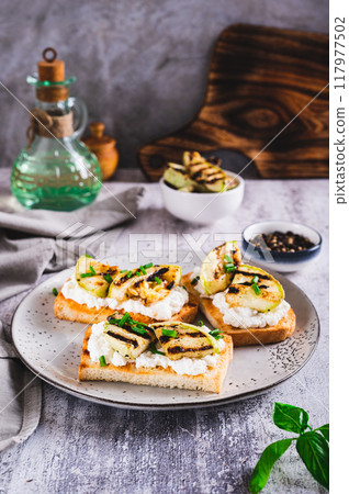Sandwiches with ricotta, grilled zucchini and green onions on a plate vertical view 117977502