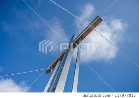 The summit cross stands tall against a backdrop of blue skies and fluffy clouds atop Wildspitze mountain, inviting mountaineers and hikers to admire the breathtaking alpine views. 117977813