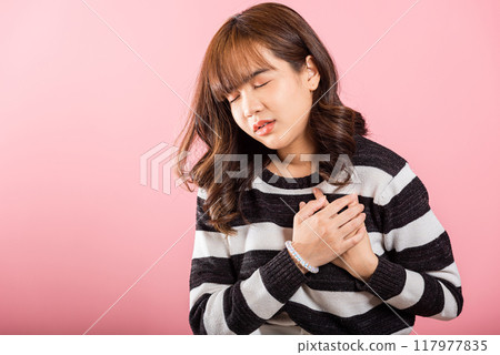 Young woman pressing on chest pain isolated on pink background, painful expression heartache, female having heart attack heart disease, Painful cramps Young woman pressing on chest pain isolated on pink background, painful expression heartache, female having heart attack heart disease, Painful cramps 117977835