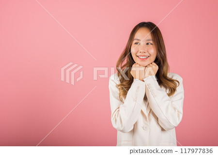 Asian happy portrait beautiful young woman standing smiling surprised excited her keeps hands pressed together under the chin studio shot on pink background with copy space for text Asian happy portrait beautiful young woman standing smiling surprised excited her keeps hands pressed together under the chin studio shot on pink background with copy space for text 117977836