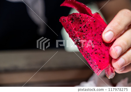 Close-up image of a piece of dragon fruit held by a caucasian man. 117978275