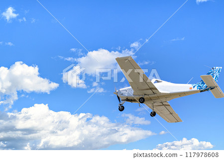 Single engine ultralight plane flying in the blue sky with white clouds Single engine ultralight plane flying in the blue sky with white clouds 117978608