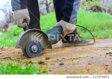 An angle grinder hand saw is used by worker when cutting metal An angle grinder hand saw is used by worker when cutting metal 117978951