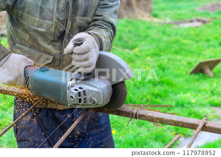 Worker cut metal frames with hand saw using angle grinder 117978952