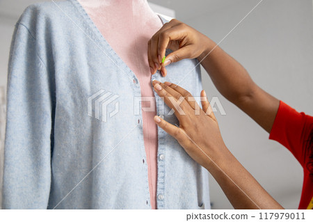 Woman fashion designer working with tailoring mannequin adjusting shirt Woman fashion designer working with tailoring mannequin adjusting shirt 117979011