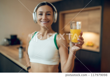 Sporty happy woman drinking detox juice after doing exercise and listening to music at home Sporty happy woman drinking detox juice after doing exercise and listening to music at home 117979098