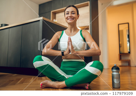 Fit attractive fit cheerful woman doing sports exercising while sitting in lotus pose 117979109