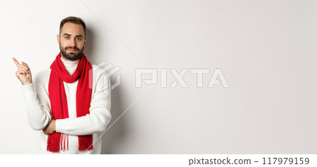 Christmas shopping and winter holidays concept. Handsome caucasian man with beard pointing finger left, showing New Year promo banner, standing over white background 117979159