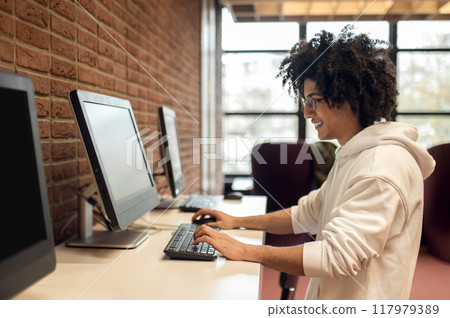 Young male student embracing technology for studying in library Young male student embracing technology for studying in library 117979389