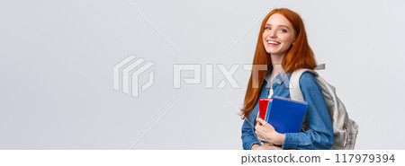 Teenagers, students and education concept. Cheerful lovely redhead female studying, going to univeristy or college, smiling carefree holding backpack and notebooks, standing white background 117979394