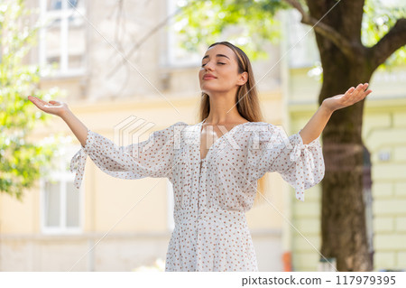 Young woman taking a deep breath of fresh air relaxing taking a break resting meditating on street Young woman taking a deep breath of fresh air relaxing taking a break resting meditating on street 117979395