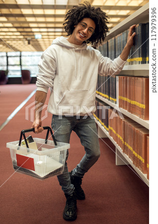 Man student in library reaching for book from shelf preparing for university seminars 117979396