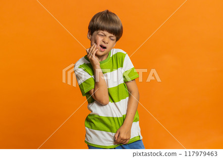 Child boy kid touching cheek, closing eyes with expression of terrible suffer from painful toothache Child boy kid touching cheek, closing eyes with expression of terrible suffer from painful toothache 117979463