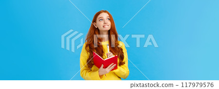 Girl full of hopes and aspirations writing down wishes in notebook. Inspired and creative attractive redhead woman looking upper left corner dreamy and hopeful, hold pen and diary, smiling 117979576
