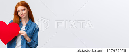 Lovely and shy, cute redhead teenage girl confess sympathy, give present on valentines day, handmade red heart, smiling silly and tender camera, express love and feelings, standing white background 117979656