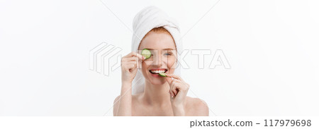 Attractive Young Woman with beautiful clean skin. White mask and cucumbers. Beauty treatments and cosmetology spa therapy. White background Attractive Young Woman with beautiful clean skin. White mask and cucumbers. Beauty treatments and cosmetology spa therapy. White background 117979698