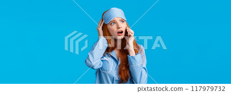 Alarmed and disappointed, upset redhead girl woke up bad news, calling friend telling bad dream via phonecall, holding smartphone near ear, talking look uneasy and anxious, blue background 117979732