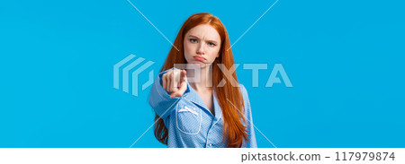 Offended timid and silly redhead teenager, girl in nightwear pointing at camera with blame, shame someone, sulking and frowning angry, accuse person, standing blue background unsatisfied Offended timid and silly redhead teenager, girl in nightwear pointing at camera with blame, shame someone, sulking and frowning angry, accuse person, standing blue background unsatisfied 117979874
