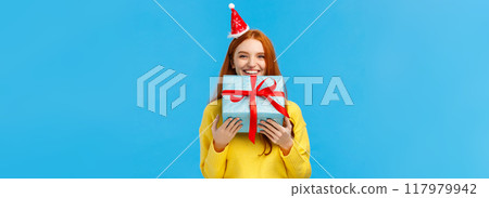 Girl cant wait give sibling her gift, smiling carry cute christmas wrapped present and wearing fancy santa hat, laughing, sharing positive emotions, attend winter holidays party, blue background Girl cant wait give sibling her gift, smiling carry cute christmas wrapped present and wearing fancy santa hat, laughing, sharing positive emotions, attend winter holidays party, blue background 117979942