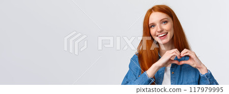 Happy valentines day, love. Cute and tender romantic redhead girlfriend showing heart sign, confess in sympathy, express passion or like, admire amazing artwork, appreciate, stand white background 117979995