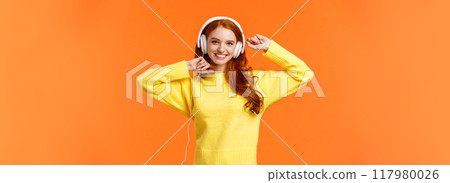 Happy and carefree excited redhead hipster girl like her new headphones, dancing with hands lifted up and smiling enjoy listening music over orange background, boost mood with favorite song Happy and carefree excited redhead hipster girl like her new headphones, dancing with hands lifted up and smiling enjoy listening music over orange background, boost mood with favorite song 117980026