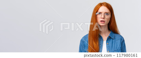 Confused and displeased, unsure redhead girl in glasses having conversation, talking look frustrated and slightly unconvinced, have doubts standing white background frowning 117980161