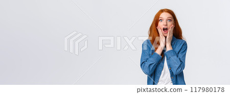 Oh my gosh, amazing. Surprised speechless redhead woman standing starled and shocked, touch face, drop jaw and stare camera fascinated, got job, won prize, standing white background Oh my gosh, amazing. Surprised speechless redhead woman standing starled and shocked, touch face, drop jaw and stare camera fascinated, got job, won prize, standing white background 117980178