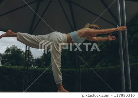 young woman athlete in sportswear practices yoga, enjoys training 117980310