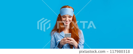 Mobile addication, technology and beauty concept. Cheerful girl waking up and grab phone, checking messages, scrolling news feed on smartphone wearing nightwear, sleep mask, smiling Mobile addication, technology and beauty concept. Cheerful girl waking up and grab phone, checking messages, scrolling news feed on smartphone wearing nightwear, sleep mask, smiling 117980318