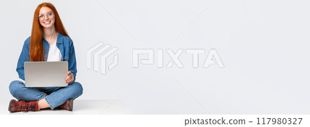 Attractive charismatic redhead caucasian female sit on floor with crossed legs, holding laptop laps, working on fresh air, writing new program, freelancing over white background 117980327