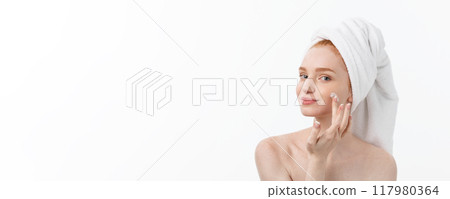 beautiful model applying cosmetic cream treatment on her face on white. 117980364