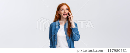 Friendly carefree pretty redhead woman talking on phone, having interesting discussion with friend on smartphone, calling mom living abroad, standing white background communicating 117980581