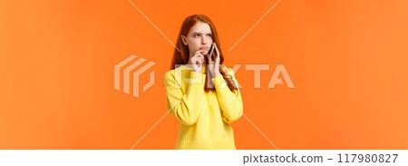 Indecisive and unsure, skeptical serious-looking redhead woman having tough decision make during conversation on phone, frowning touch lip pensive, order food delivery, orange background Indecisive and unsure, skeptical serious-looking redhead woman having tough decision make during conversation on phone, frowning touch lip pensive, order food delivery, orange background 117980827