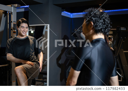 Trainer and client teaching stretching and muscle training at gym Trainer and client teaching stretching and muscle training at gym 117982433