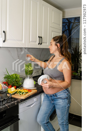 Pregnant woman making healthy smoothie. Healthy lifestyle in pregnancy Pregnant woman making healthy smoothie. Healthy lifestyle in pregnancy 117982973