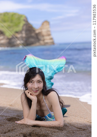 夏天，年輕的女美人魚在沙灘上睡覺和微笑 117983536