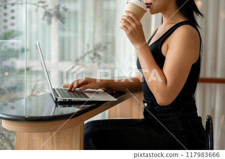 A woman enjoying coffee while working remotely from a modern, minimalist coffee shop. A woman enjoying coffee while working remotely from a modern, minimalist coffee shop. 117983666