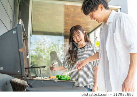 Men and women having barbecue, camping, BBQ, grilled meat, glamping (home party, balcony camping) 117983693
